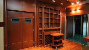 A wooden interior with a sliding door, built-in shelves, and a wheeled cart. - Cezar Hotel (Banja Luka)