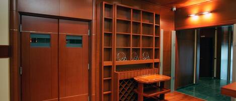 A wooden interior with a sliding door, built-in shelves, and a wheeled cart.