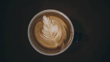 A cup of coffee with a leaf design on the surface.