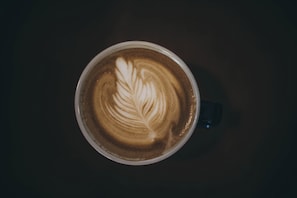 A cup of coffee with a leaf design on the surface. - Bristol (Mostar)