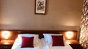 A double room with two beds, each with a pillow and a folded towel. There is a framed picture on the wall and a patterned curtain. - Bristol (Mostar)