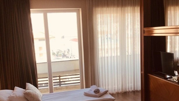 Quarto de hotel com cama, televisão e vista para o exterior.