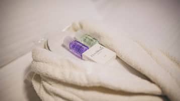 A white towel with a bottle of lotion and a small box, possibly a toiletry item, on a bed.