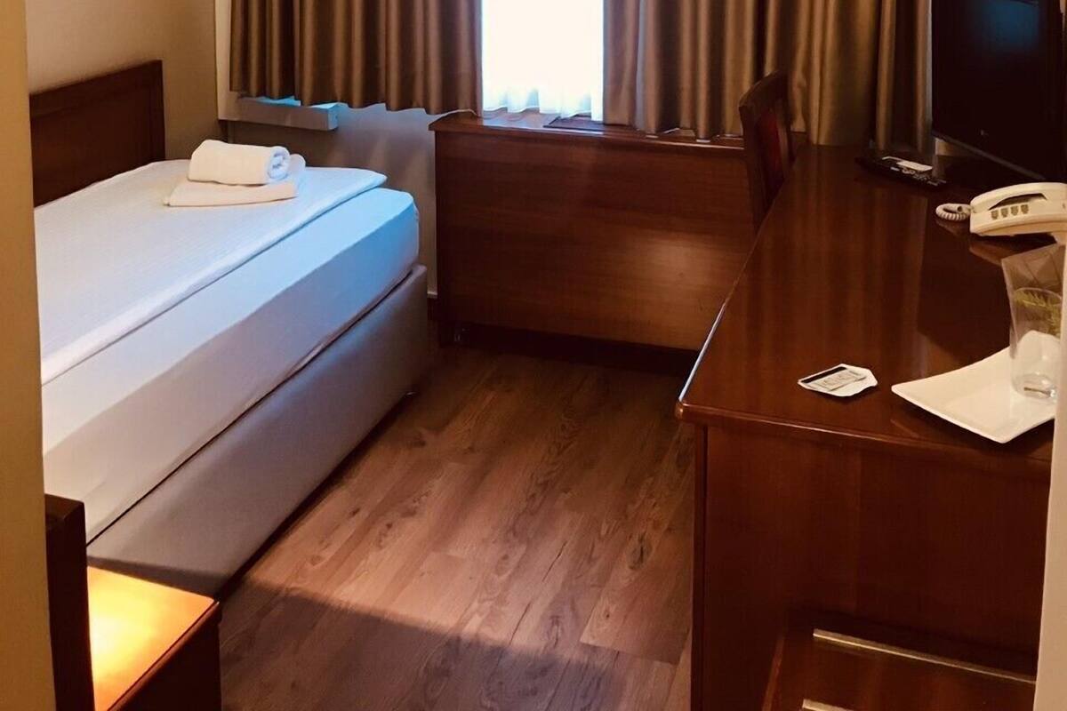 Een hotelkamer met een bed, een bureau, een televisie en een airconditioning.