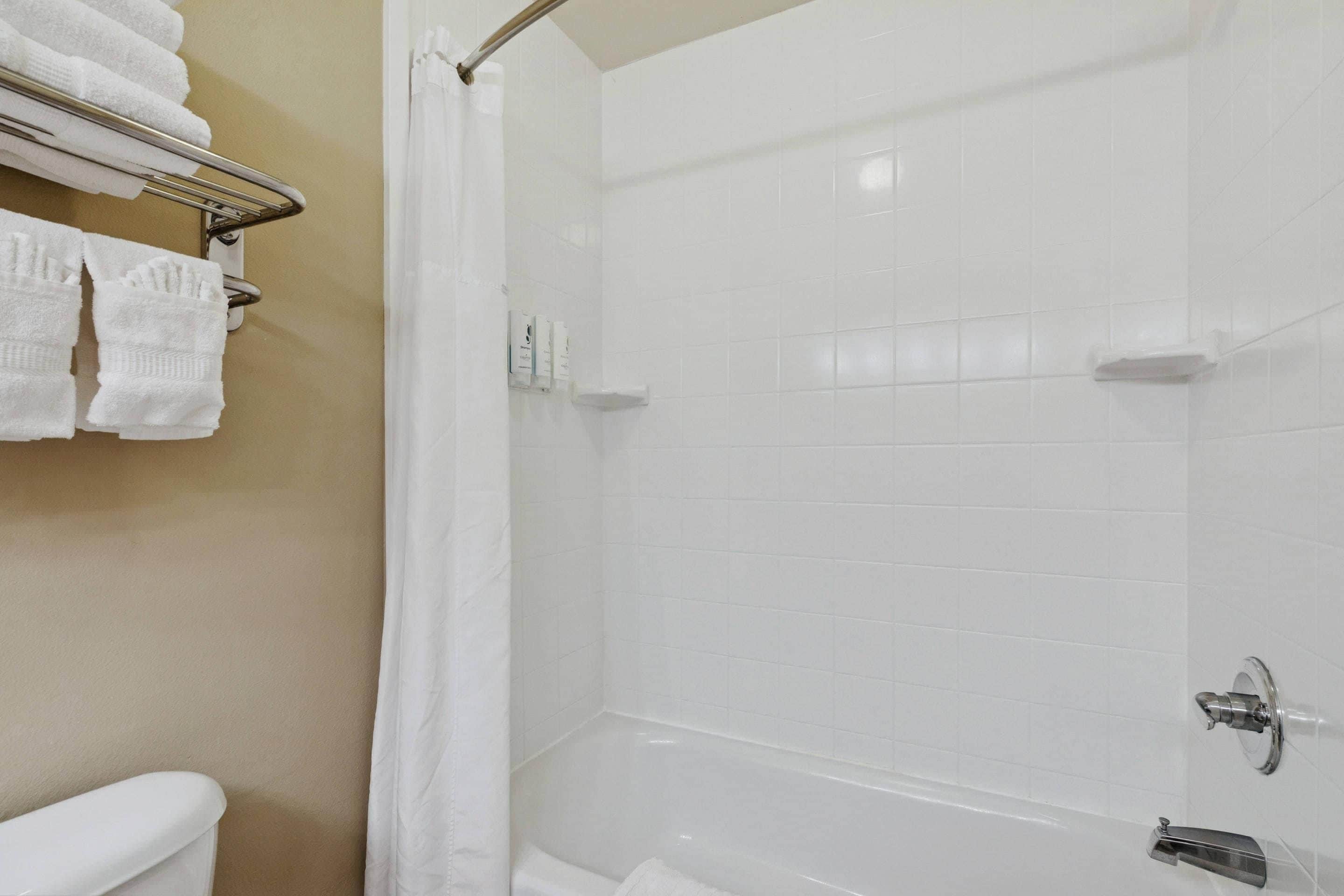 A bathroom with a white bathtub, a shower curtain, and a towel rack with folded towels.