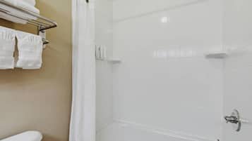 A bathroom with a white bathtub, a shower curtain, and a towel rack with folded towels.