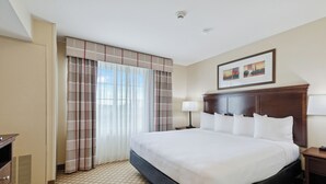 A hotel room with a large bed, a wooden headboard, a nightstand, a lamp, a wardrobe, and a window with curtains. - Country Inn & Suites by Radisson, Covington, LA (Covington)