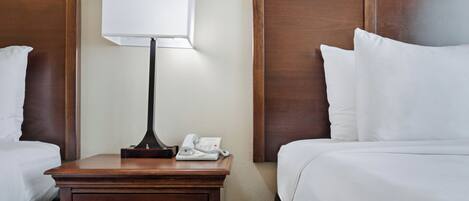 Ein Hotelzimmer mit zwei Betten, einem Nachttisch mit Lampe und Telefon sowie einem Schubladenschrank.
