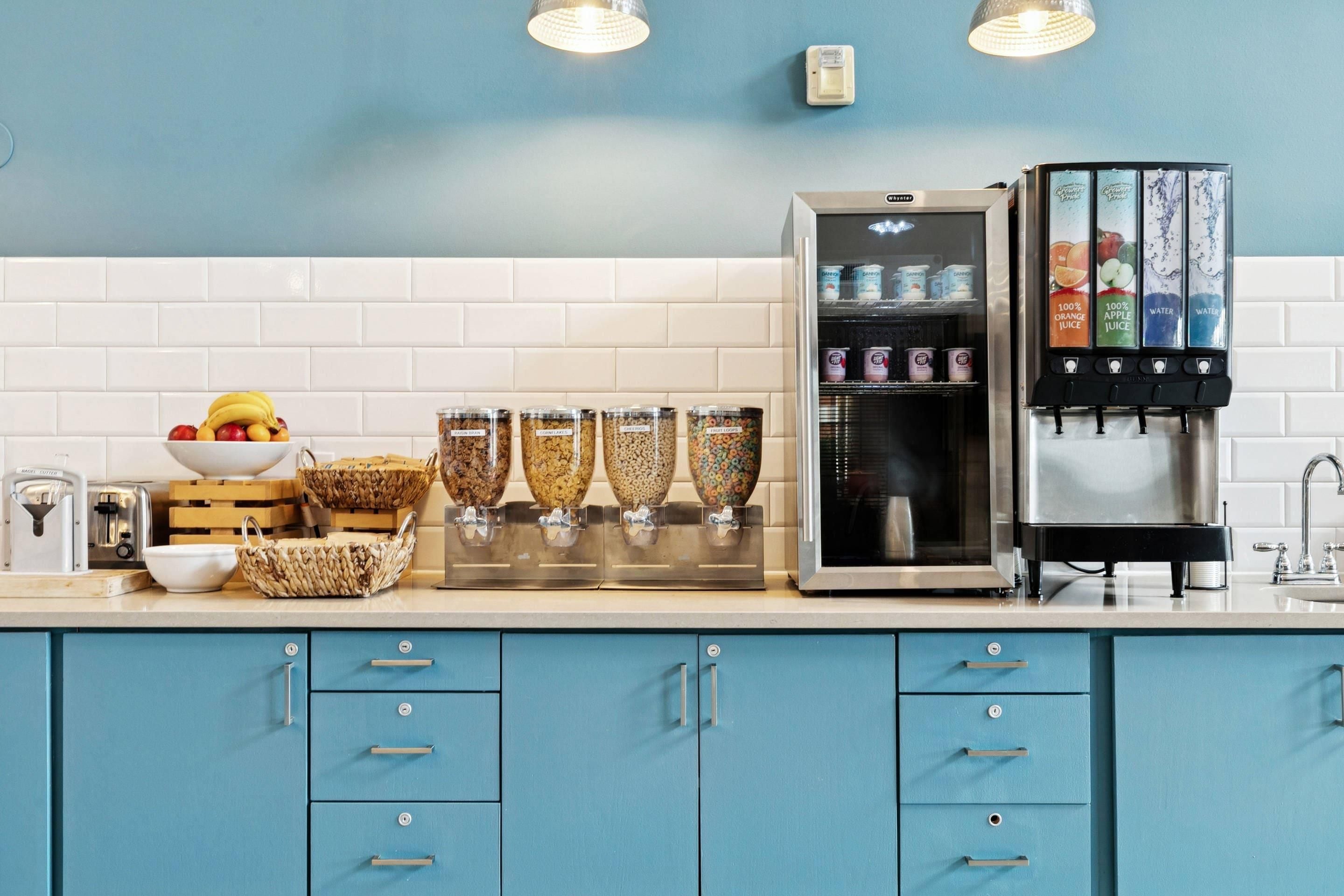 A kitchen with a refrigerator, a fruit bowl, and a water dispenser.