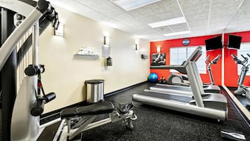 A gym with cardio equipment, weight machines, and a red accent wall.