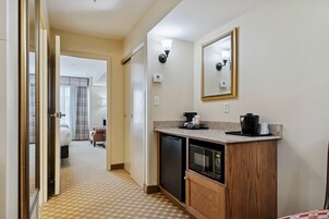 Habitación de hotel con kitchenette, microondas, cafetera y espejo.