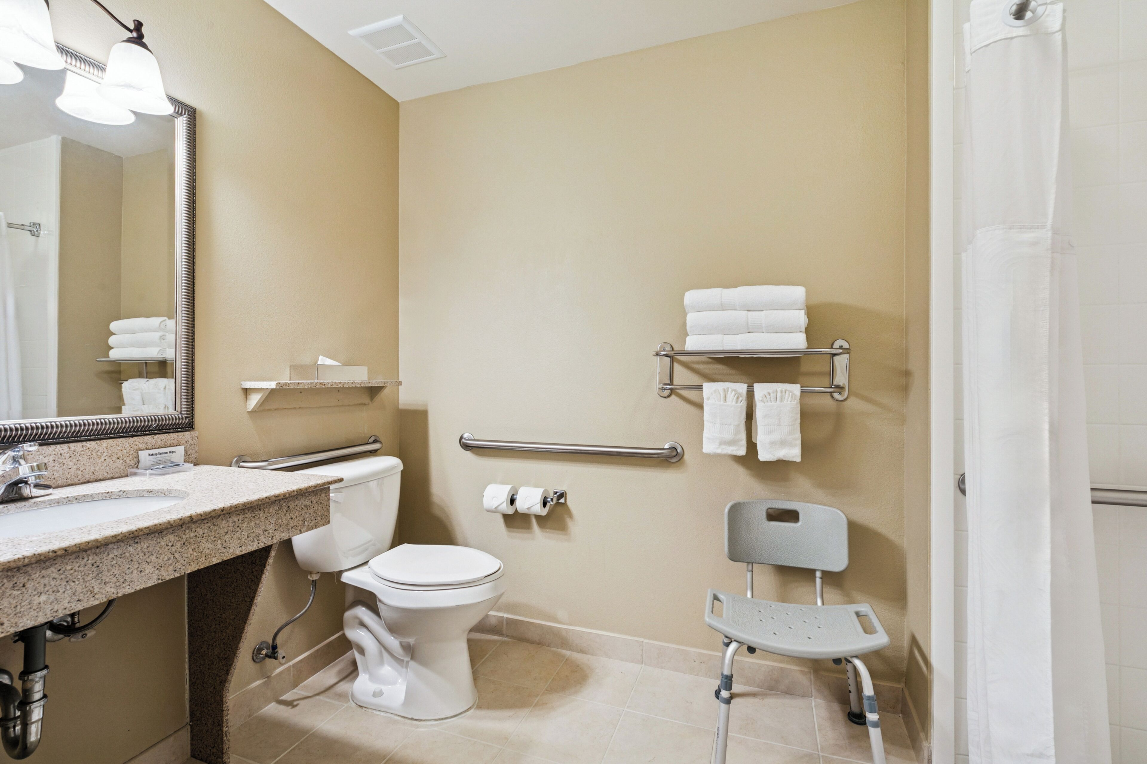 A bathroom with a sink, toilet, mirror, towel rack, and shower curtain.