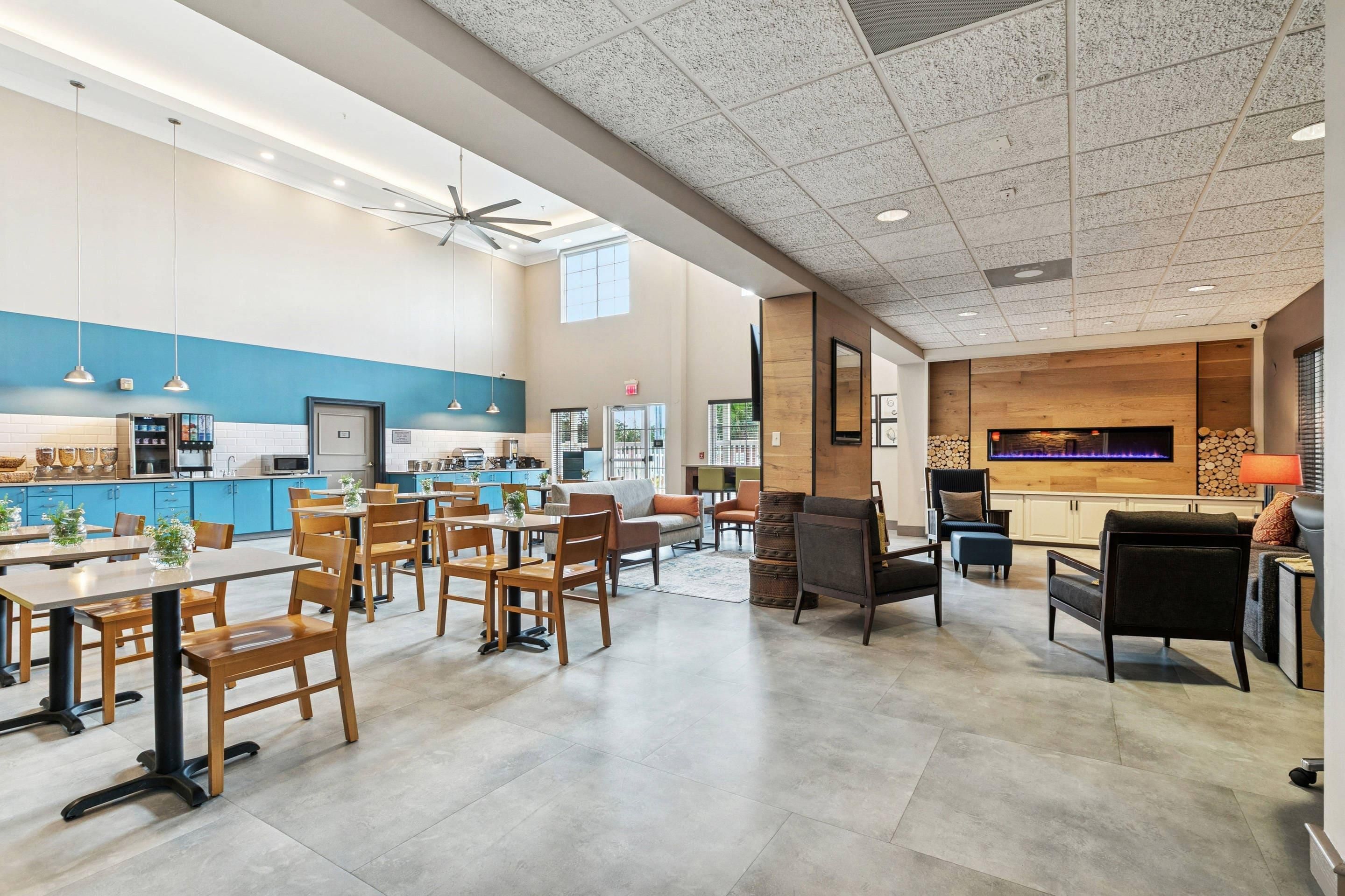 A spacious dining area with wooden tables and chairs, a kitchen area with blue cabinets, and a living area with a fireplace and comfortable seating.