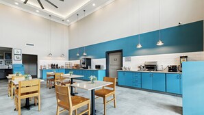 Una cocina moderna con armarios azules, encimeras blancas y mesas y sillas de madera.