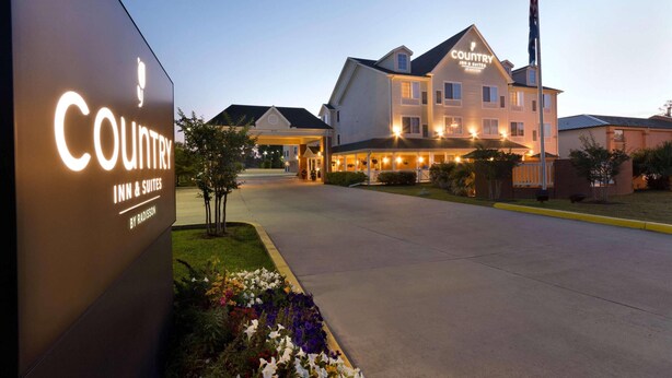 Edificio de Country Inn & Suites con una entrada bien iluminada y un asta de bandera.