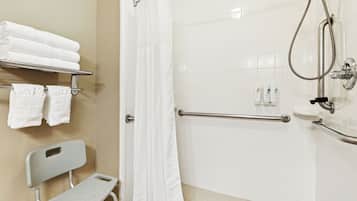 A bathroom with a shower, grab bars, a bench, and a towel rack.