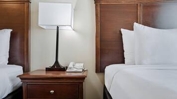 A hotel room with two beds, a nightstand with a lamp, and a telephone.