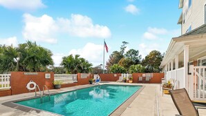 Una piscina con un letrero que prohíbe el clavado, sillas de descanso e izado de la bandera estadounidense.