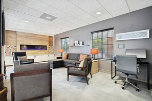 A modern office space with a fireplace, seating area, and a desk with a computer. - Country Inn & Suites by Radisson, Covington, LA (Covington)