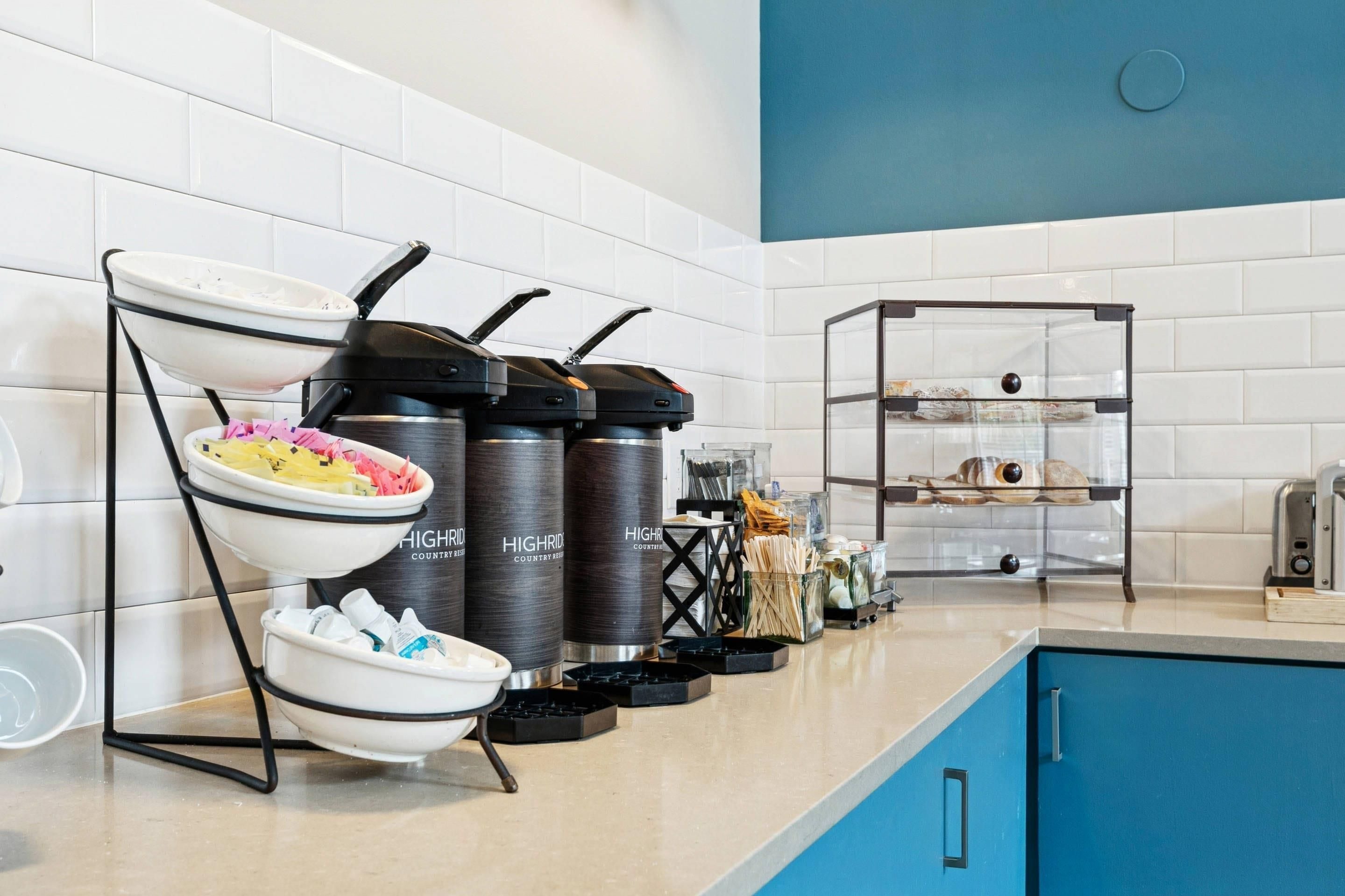 A kitchen area with a buffet setup, including a bowl of food, condiment dispensers, and a glass display case.