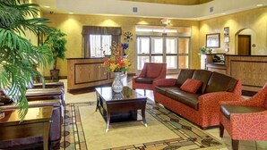 A lobby with a mural of Alvarado, Texas, a reception desk, a coffee table with a vase of flowers, a sofa, and chairs. - Comfort Inn & Suites Alvarado (Alvarado)