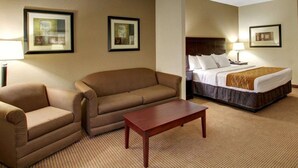 A hotel room with a bed, two sofas, a coffee table, and framed artwork on the walls. - Comfort Inn & Suites Alvarado (Alvarado)