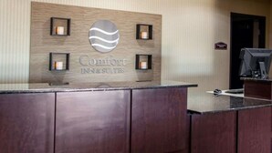 Una recepción de hotel con un letrero que dice "Comfort Inn & Suites" y un cartel de "Oficinas de cortesía" encima.
