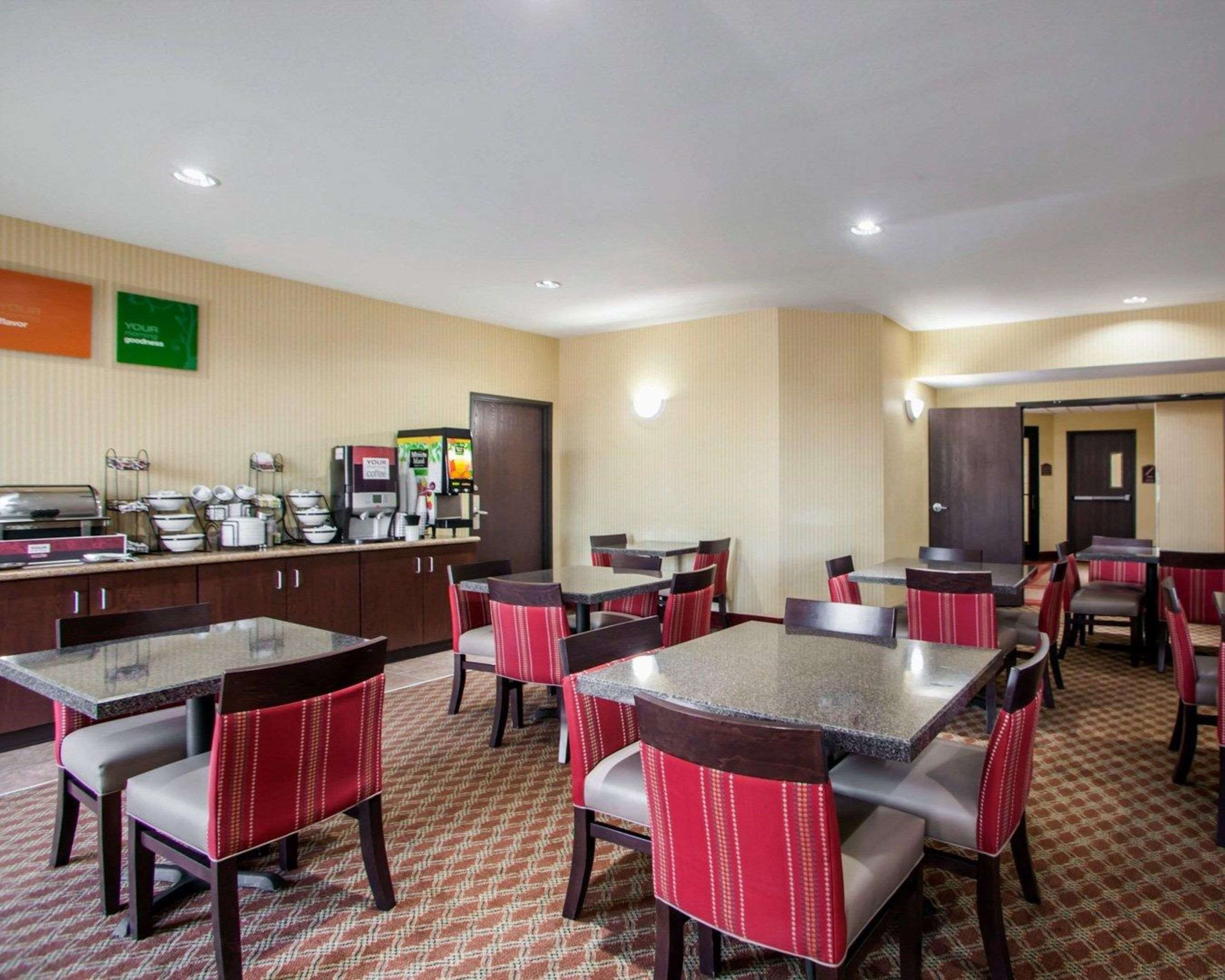 A hotel dining area with multiple tables and chairs, a coffee station, and a counter with various food items.