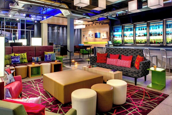 Un espace de détente moderne, doté de différents types de sièges, d’un bar et offrant une vue sur le paysage urbain.