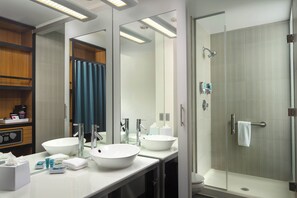 Ein modernes Badezimmer mit zwei Waschbecken, einem großen Spiegel und einer Duschkabine.