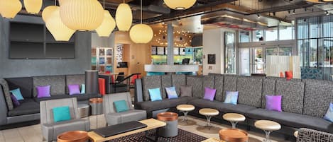 Un espace de détente moderne avec des canapés, des tables et des lampes suspendues.