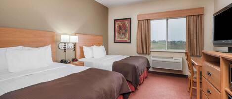 A hotel room with two beds, a desk, a chair, a TV, and a window with curtains.