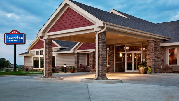 An American Inn hotel with a covered entrance, brick pillars, and a landscaped front yard. - AmericInn by Wyndham Anamosa (Anamosa)