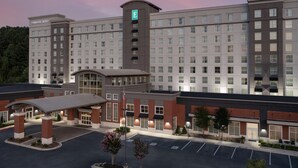 A multi-story hotel with a prominent entrance, a parking lot, and a landscaped area with trees. - Embassy Suites by Hilton Birmingham Hoover (Birmingham)