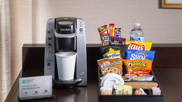 Máquina de café, placa indicando suíte premium e bandeja com batatas fritas e biscoitos.