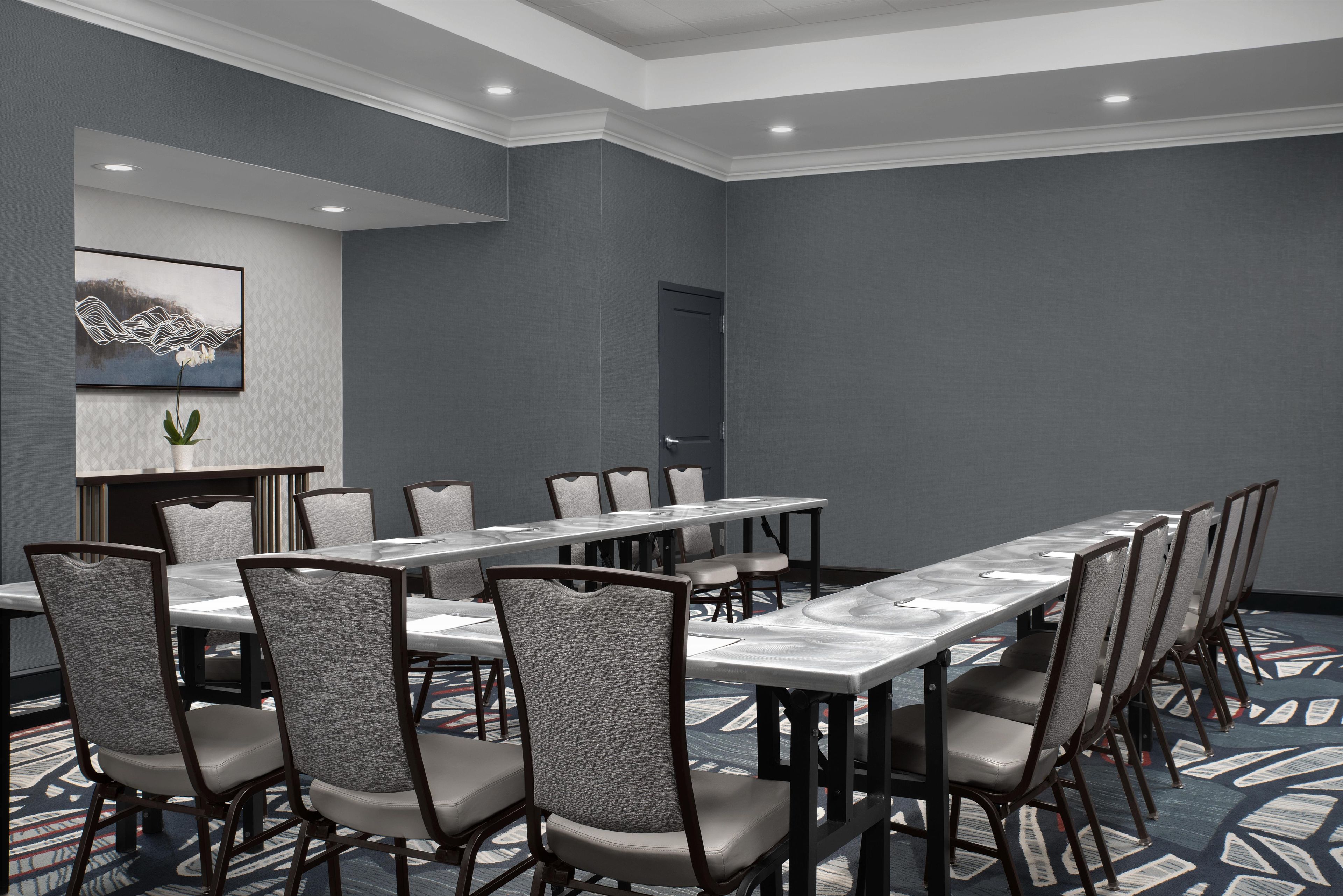 A conference room with a long table, chairs, and a door.