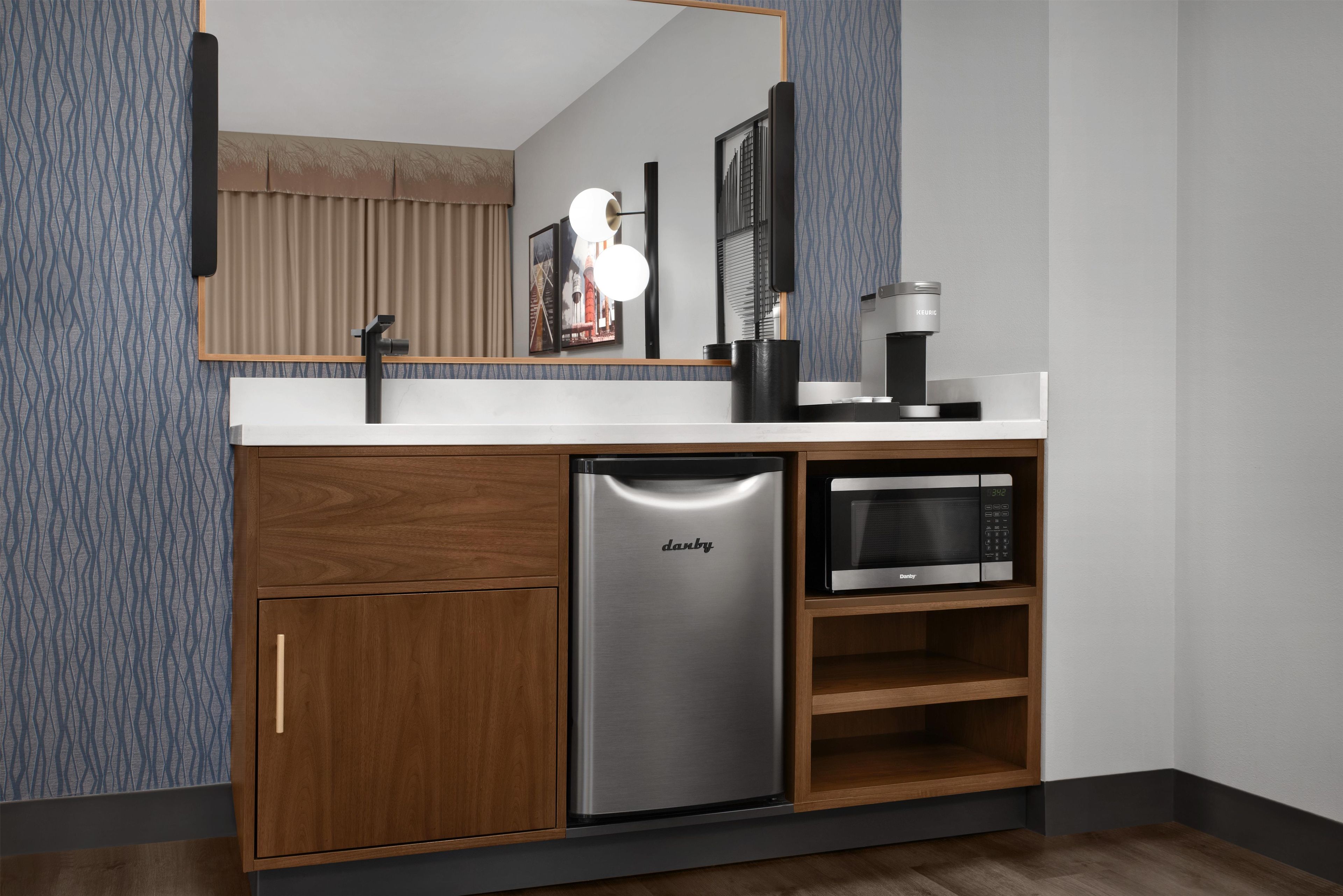 A compact kitchen with a built-in refrigerator, microwave, and coffee maker.