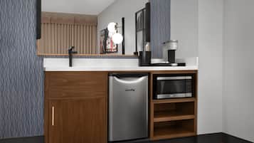 A compact kitchen with a built-in refrigerator, microwave, and coffee maker.