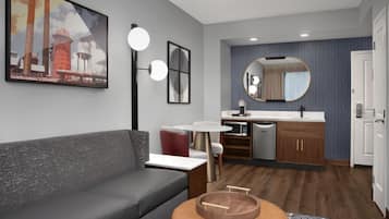 Un salón moderno con un sofá gris, una mesa de centro redonda y un cuadro de estructuras industriales.