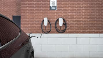 A car charging at an electric vehicle parking station with a sign indicating it is for hotel guests only.