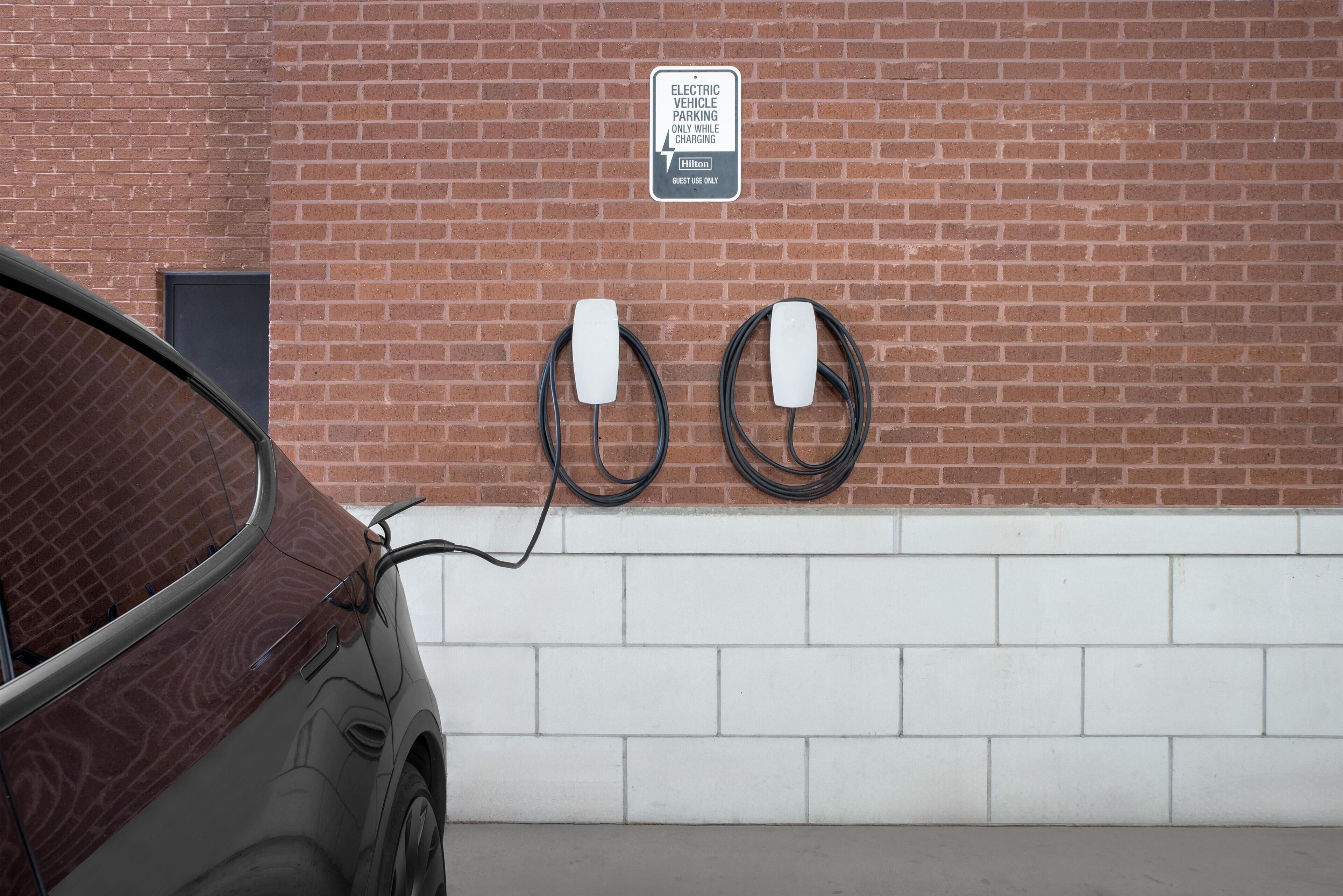 A car charging at an electric vehicle parking station with a sign indicating it is for hotel guests only.