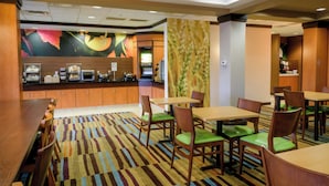 Eine Hotelhalle mit einem Buffetbereich, mehreren Sitzgelegenheiten und einem gemusterten Teppich.