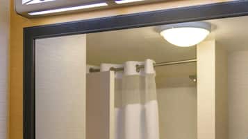 A bathroom with a large mirror, a sink, and a shower curtain.