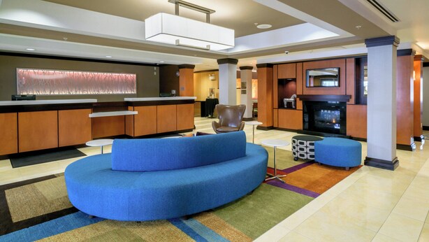 Eine moderne Lobby mit einem gewölbten blauen Sofa, einem Empfangstresen, einem Fernseher und einem Kamin.