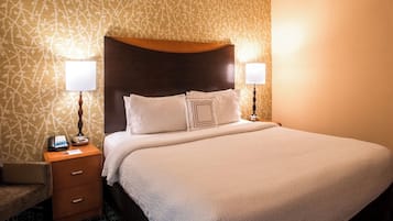 A neatly made bed with a headboard, two bedside lamps, a nightstand with a phone and a notepad, and a patterned wall.