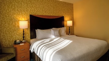 A hotel room with a bed, two bedside lamps, a nightstand, and a patterned wallpaper.