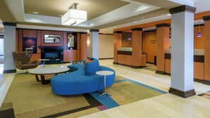 Eine moderne Lobby mit einem blauen Sofa, einem Kamin und einem kleinen Tisch.