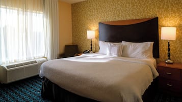 Habitación de hotel con una cama grande, dos lámparas de noche, un teléfono y un calentador.