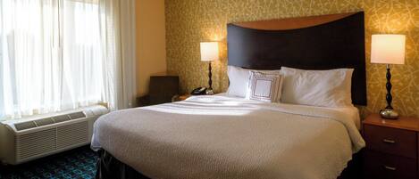 A hotel room with a large bed, two bedside lamps, a telephone, and a heater.