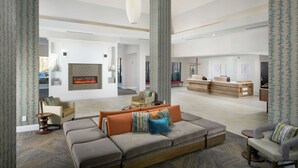Un amplio salón con un sofá seccional, una chimenea y un mostrador de recepción.